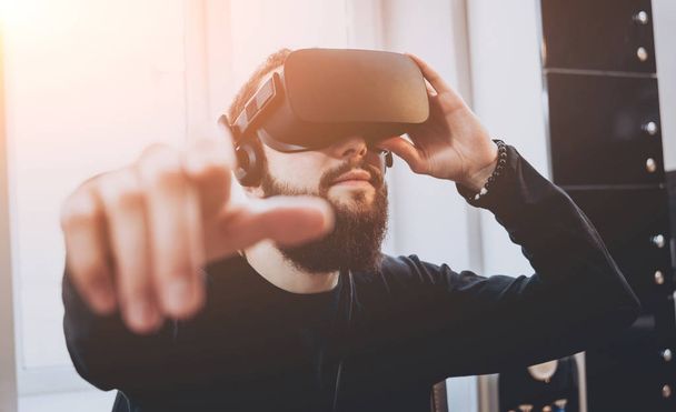 Young man with beard wearing virtual reality goggles at the office - Foto, Imagen