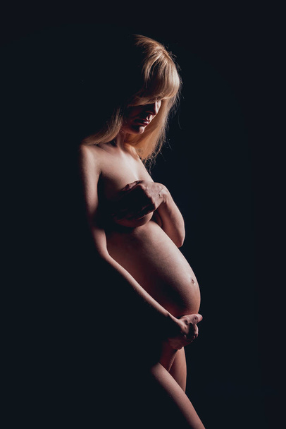 Silhouette of beautiful nude pregnant woman. Low key light - Foto, afbeelding