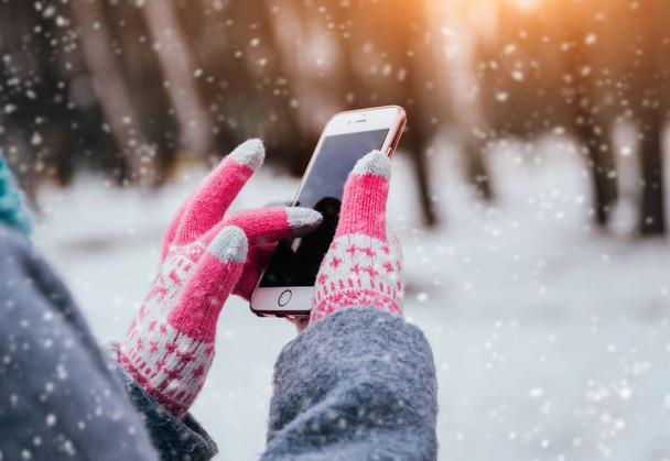 Woman using smartphone with pink gloves for touch screens in winter. - Photo, image