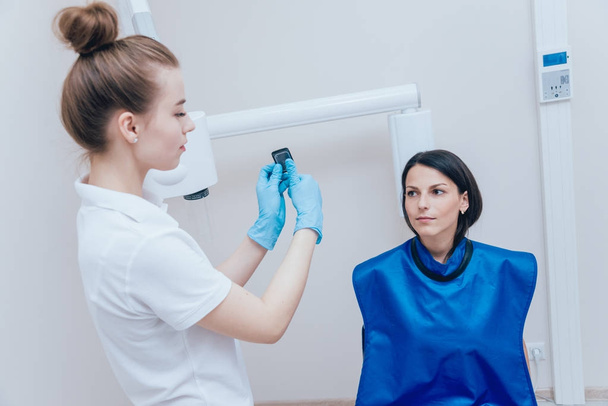 Dentist make x-ray image for young woman in dental clinic. Aiming dental radiography. - Valokuva, kuva