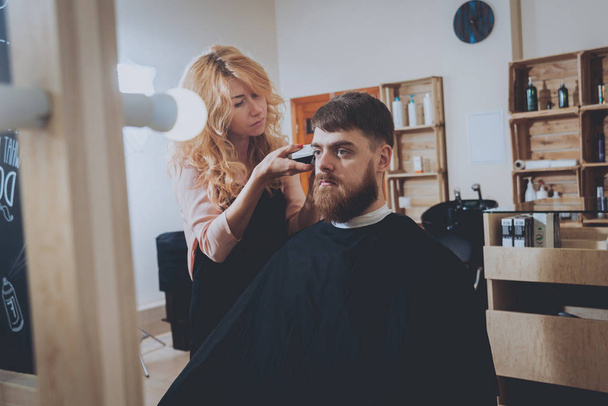 Master cuts hair and beard of men, hairdresser makes hairstyle for a young man. - Photo, Image