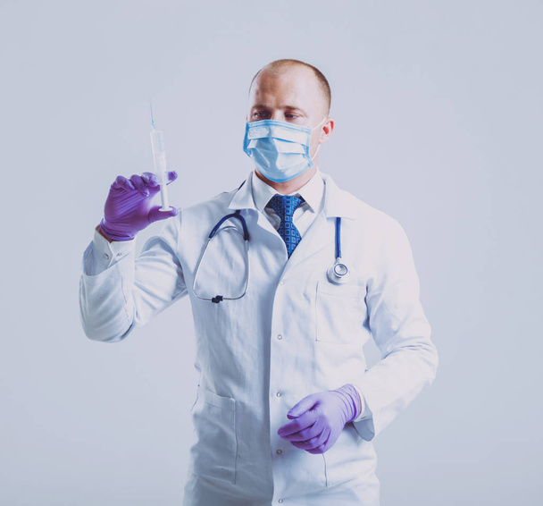 Adult caucasian blue eyed doctor posing with different medical things before white wall with copy space - Fotó, kép