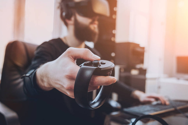 Young man with beard wearing virtual reality goggles at the office - Photo, Image