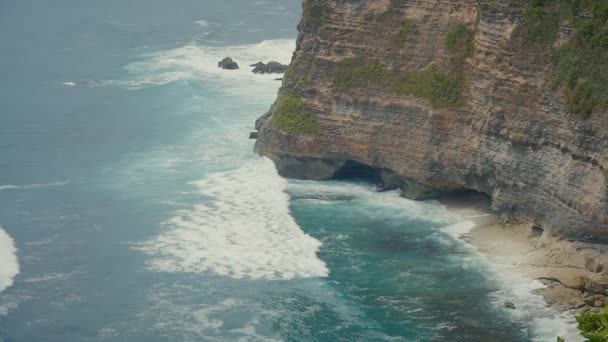 Okyanus dalgaları taş uçurumlarda kırma. Tropikal Beach Bali, Endonezya Hava üstten görünüm. Ağır çekim - Video, Çekim
