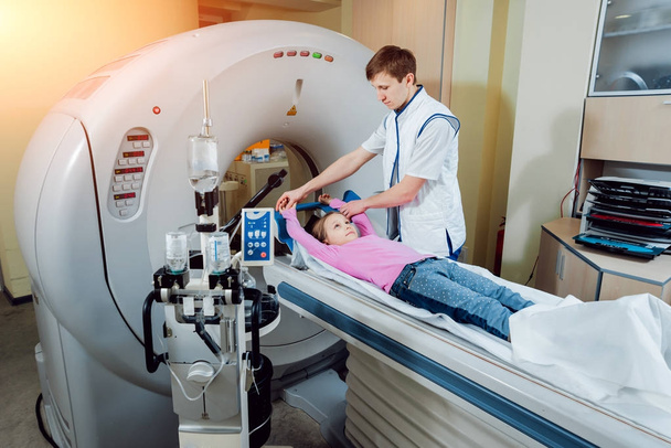Equipo médico. Médico caucásico masculino y paciente niña en sala de tomografía computarizada en el hospital
. - Foto, imagen