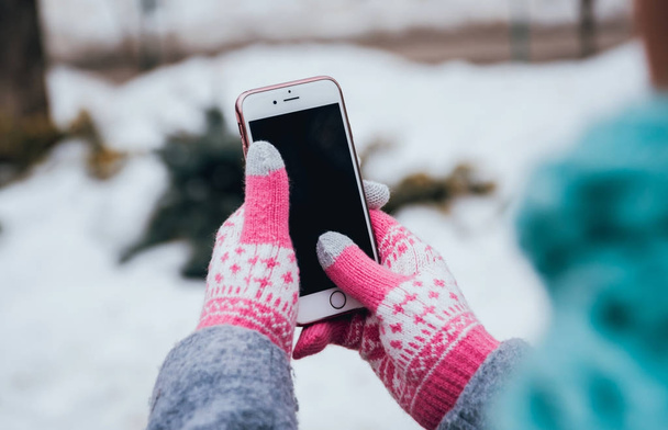 Woman using smartphone with pink gloves for touch screens in winter. - Zdjęcie, obraz
