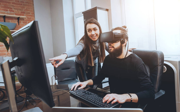Young man with woman creative office workers testing VR goggles and having fun - Foto, imagen