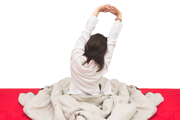 Woman stretching on the bed after waking up, back view, isolated background - Foto, Bild