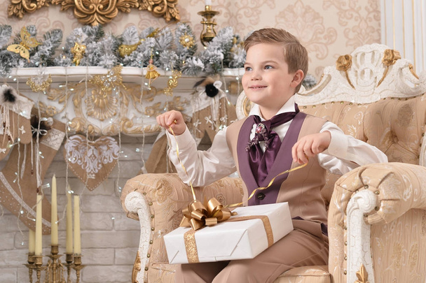 Portrait of little boy  with gift near Christmas tree - 写真・画像