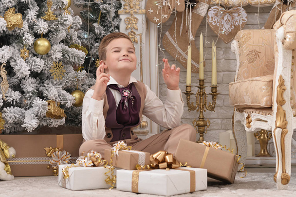 Portrait of little boy  making wish near Christmas tree - Photo, image