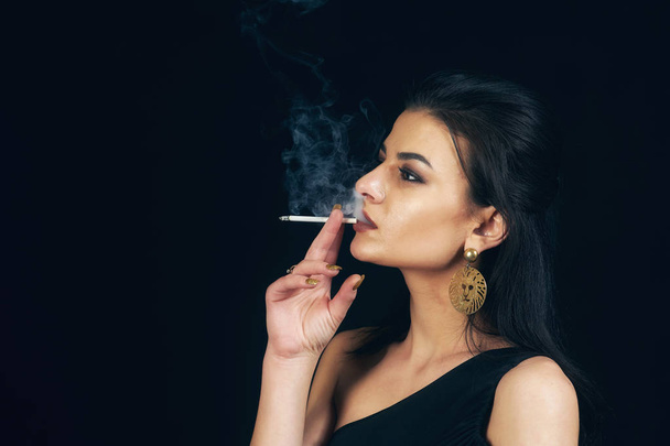 Žena kouření cigarety na černém pozadí . - Fotografie, Obrázek