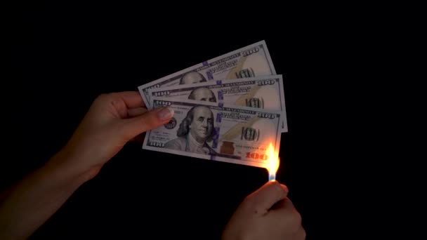 Burning dollars in a hand close-up on a black background. Slow motion - Filmati, video