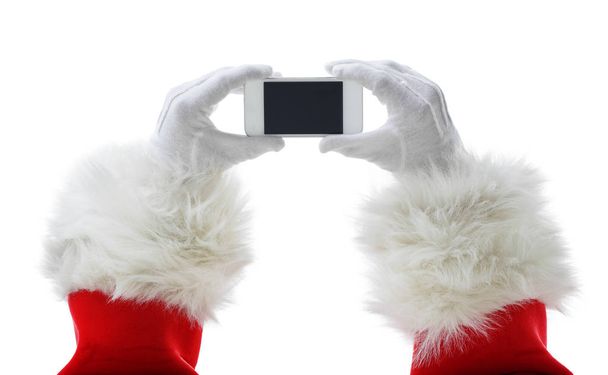 Christmas concept shot with Santa holding a white smart phone Isolated on white - Photo, image