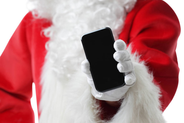 Christmas concept shot with Santa holding a black smart phone, showing it into the camera - Foto, Imagem