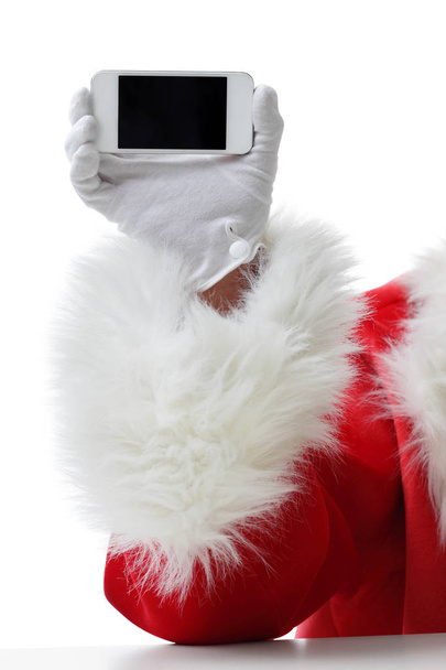 Christmas concept shot with Santa holding a white smart phone Isolated on white - Foto, immagini