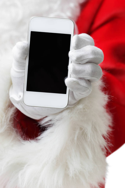 Christmas concept shot with Santa holding a white smart phone Isolated on white - Foto, Bild
