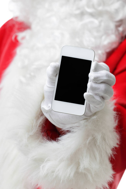 Christmas concept shot with Santa holding a white smart phone Isolated on white - Foto, Imagem