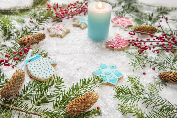 festive Christmas, New Year's screensaver, postcard, background. Homemade bright gingerbreads, branches of a Christmas tree, snow and a burning candle on a light background .. the mood of the holiday and the magic. - Foto, Imagem