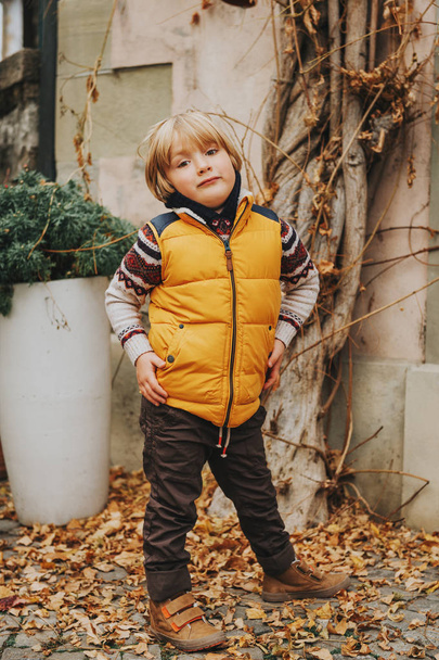 Retrato al aire libre de un lindo niño de 4-5 años, con chaleco amarillo cálido
 - Foto, imagen