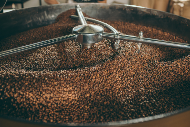 close up view of coffee beans roasting in machine - Foto, afbeelding
