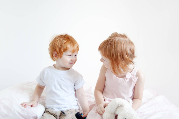 Red-haired brother and sister are sitting on the bed - Foto, Imagen