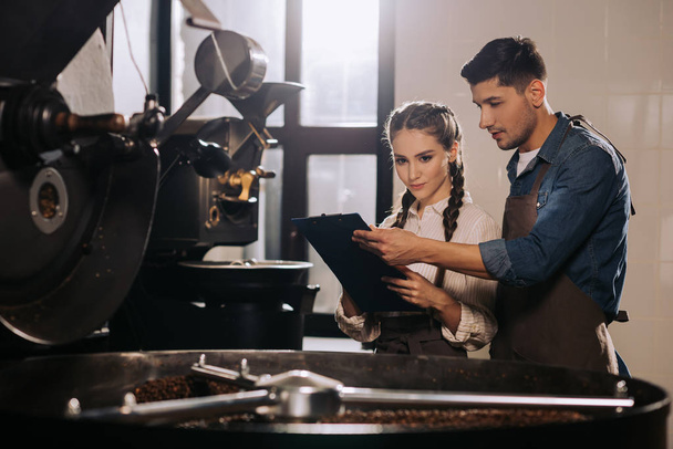 trabajadores de la cafetería revisando el proceso de tostado de granos de café juntos
 - Foto, Imagen