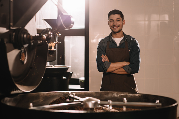 πορτρέτο του χαμογελώντας καφέ roaster στέκεται στην μηχανή ψησίματος και βλέπουν τα φωτογραφικών μηχανών - Φωτογραφία, εικόνα