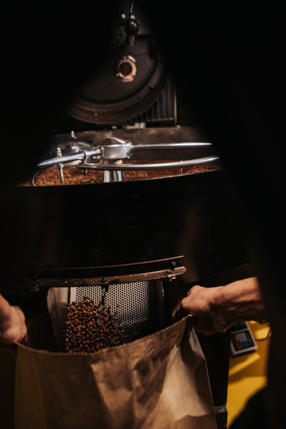 partial view of coffee roaster working on roasting machine - Foto, afbeelding