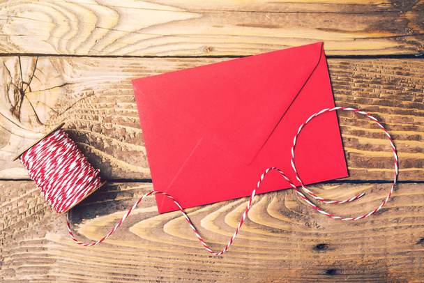 Rode en witte touw roll en rode envelop op een houten tafel. Bovenaanzicht. - Foto, afbeelding
