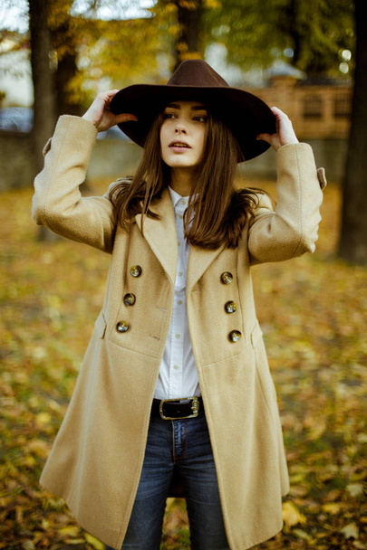 Attractive young woman in fashionable hat posing in autumnal park  - Foto, Imagem