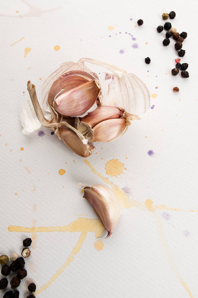 Garlic cloves lie on a white textured background with watercolor - Foto, Imagen