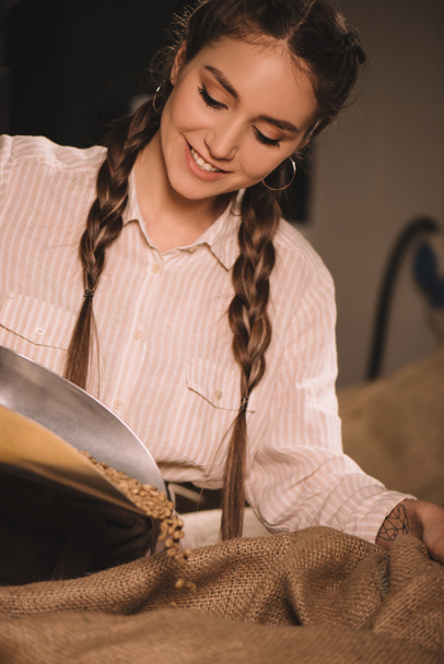 portret uśmiechający się pracownika nalewania ziarna kawy do worek worek - Zdjęcie, obraz