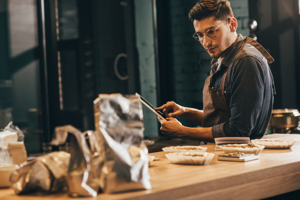 side view of focused worker in apron with tablet in coffee shop - Fotó, kép