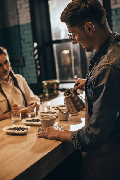 man gietend heet water in de kom met grind koffie tijdens koffie voedsel functie bij koffie shop - Foto, afbeelding