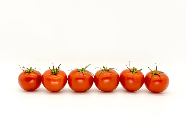 Red tomatoes in a row on a white background - Φωτογραφία, εικόνα