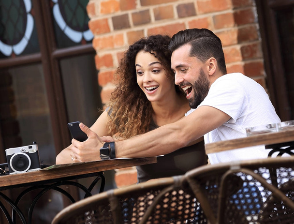Lovely young couple looking at smart phone at cafe - Foto, Imagem