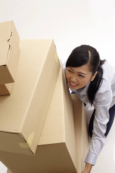 high angle view of asian woman lifting stack of boxes - Photo, image