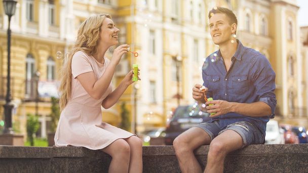 Beautiful couple blowing bubbles and having fun on sunny summer day, romance - Fotoğraf, Görsel