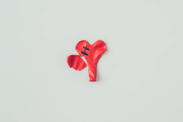 top view of broken heart shaped balloon with insulating tape isolated on white, valentines day concept  - Photo, Image