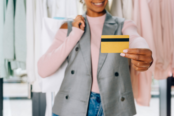 красивая молодая женщина показывает кредитную карту в магазине одежды
 - Фото, изображение