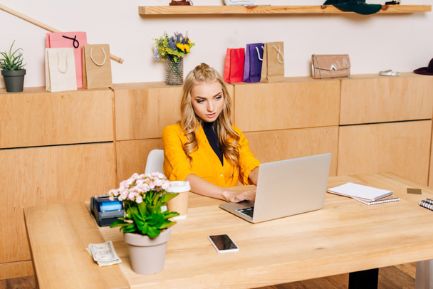 gerente de tienda de ropa utilizando el ordenador portátil en el lugar de trabajo
 - Foto, imagen