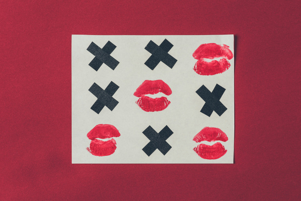 top view of tic-tac-toe with black crosses and lips prints isolated on red, valentines day concept - Photo, Image