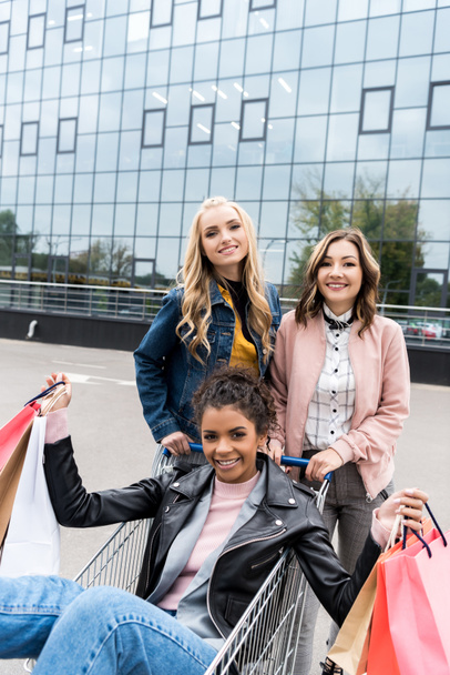 Gruppe glücklicher junger Frauen mit Einkaufswagen auf Parkplatz - Foto, Bild