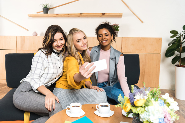 group of smiling young girlfriends taking selfie in cafe - Photo, Image