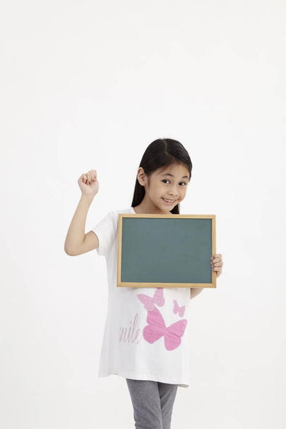 Cute little girl holding a chalkboard, isolated on white - Photo, Image