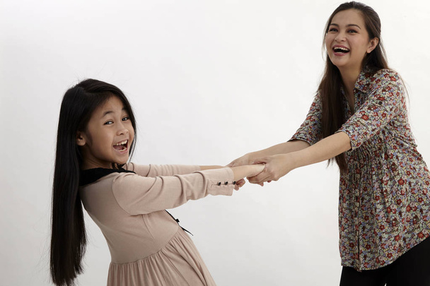mother and daughter pulling each other posing in studio - Foto, imagen