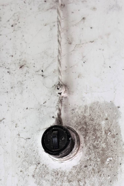 Винтажный советский черный круглый простой одиночный выключатель в паутине паука на гранж-стене
 - Фото, изображение