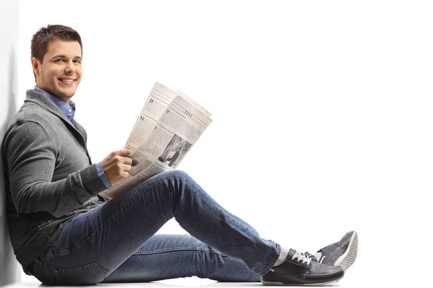 man with a newspaper sitting on the floor  - Zdjęcie, obraz