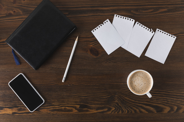 flat lay with smartphone, notebook, pencil and cup of coffee on wooden tabletop - Photo, Image