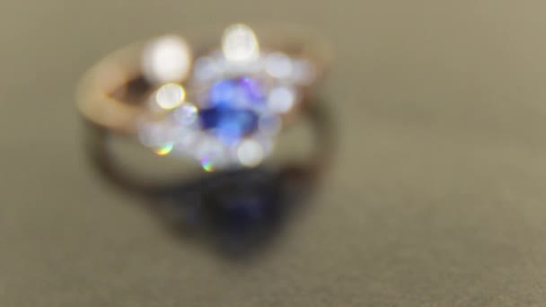 Prachtige vrouwelijke gouden verlovingsring met edelstenen met blauwe saffier en white jade op een zwarte achtergrond - Video